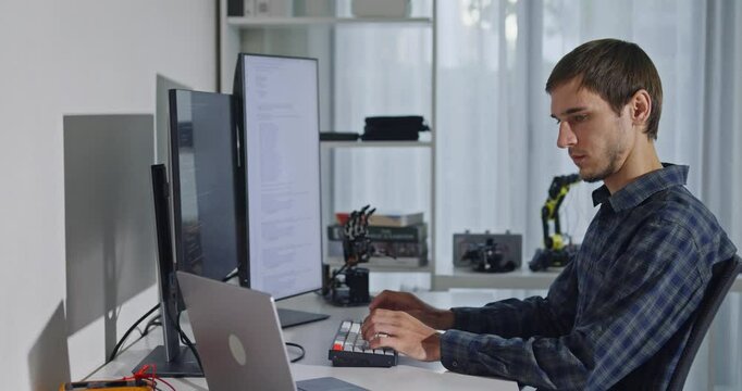 Young adult male freelance developer typing write prompt AI bot app program nomad terminal with coding at office. Artificial intelligence dashboard, robotics, user interface, machine learning concept.