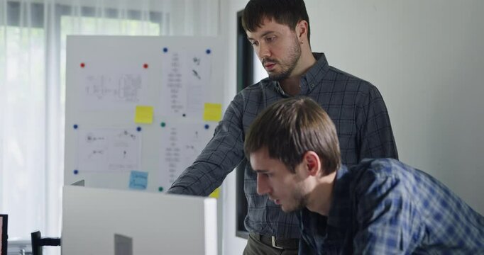 Team adult male engineer collaborate on robotic hand project using AI code solutions machine learning at tech workspace. Artificial intelligence interface, collaboration support prototype development.