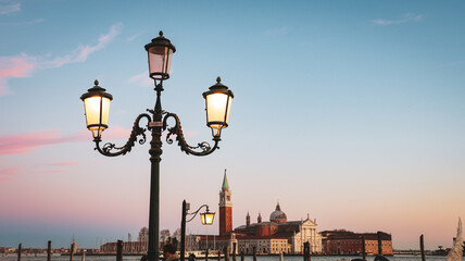 Venice sunset with street lamps illuminating the canal view