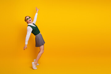 Cheerful teenage girl in a stylish outfit posing joyfully against a vibrant yellow background with...