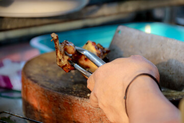 Preparing Grilled Food with Tongs on Wooden Board