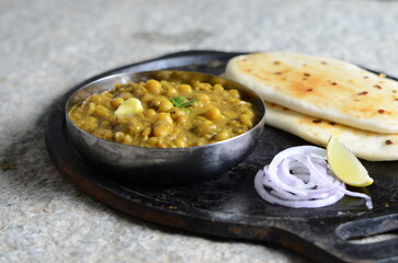 Traditional Delhi street food matar kulcha – spicy white peas curry served with soft fluffy kulcha bread, garnished with onions, lemon – North Indian vegetarian meal close-up