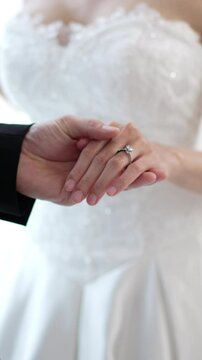 Close up of Romantic groom putting wedding ring on bride finger, elegant asian couple sharing love on special ceremony day