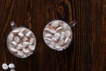 Hot chocolate with marshmallows in glass mug on wooden background