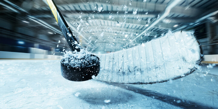 Hockey stick striking black puck on snowy ice surface under 3D arena lighting, high-speed motion blur. Concept of motion, speed, and reaction time in competitive ice hockey gameplay