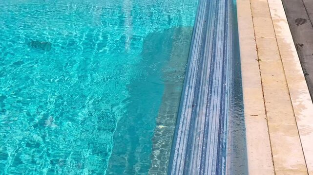 The automatic cover partially closes the pool with clear blue water. Sunlight reflections on the surface add a sense of freshness and comfort
