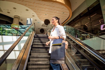 Smiling woman going up on an escalator at a local shopping mall