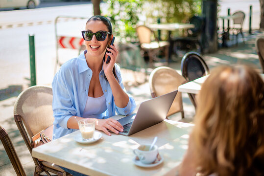 Happy brunette haired woman sitting in an outdoor cafe and working