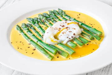 White Plate of Asparagus Nestled in Hollandaise Sauce With Poached Egg
