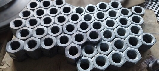 Flanged steel hex nuts stacked on the table. Tool. Steel Screw Nuts. Hex nuts in a pattern. Mechanical engineering. Is used in such fields as mechanical engineering, oil and gas, metallurgy, chemical,