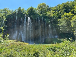 The mesmerizing waterfall at Plitvice Lakes, Croatia, flows between mountains and lush summer...