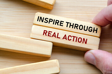 Inspire through real action message displayed on wood blocks, reflecting how true influence comes from doing rather than just speaking or commanding