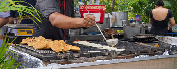 Taiyaki being prepared at street food stall with traditional griddle. Outdoor culinary scene with cooks in action.