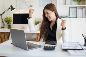 Excited businesswoman celebrating success in front of her laptop.