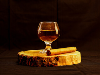 Glass of Whiskey and Cigar on Wooden Log Slice with Dark Background