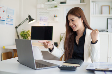 Excited businesswoman celebrating success in front of her laptop.