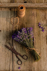 Rustic bundle of dried lavender flowers with vintage scissors and jute twine on old wooden table. Flat lay still life scene.