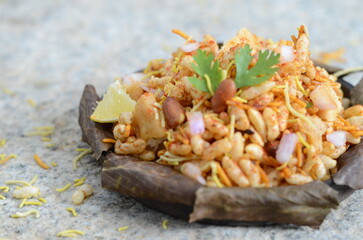 Classic Indian street food bhel puri – puffed rice mixed with sev, chutneys, onions, tomatoes, coriander, and spices – tangy and crunchy chaat served in paper plate,