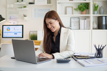 Happy female entrepreneur working with laptop in modern workspace.