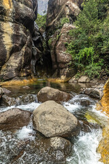 The narrow crack, forming the entrance to the slot canyon known as the Tugela tunnel, with a small rapid in the river in the foreground, in the Drakensberg Mountains of South Africa.