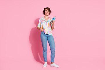 Full length portrait of nice young lady use smart phone empty space wear shirt isolated on pink...