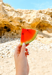 Hand Holding Watermelon Slice on a Sunny Beach