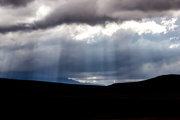 Sunrays breaking through the ominous thick clouds with distant blue mountains of the Drakensberg...
