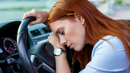 Tired woman asleep at the wheel inside car, concept of driver fatigue, drowsiness danger and road safety.