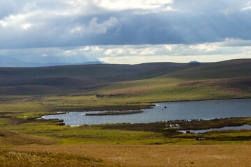 Sunrays breaking through the clouds over the grasslands and a small lake in the Drakensberg mountains of South Africa
