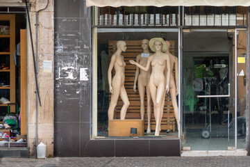 Nude mannequins in display window of clothing store that's closing down.