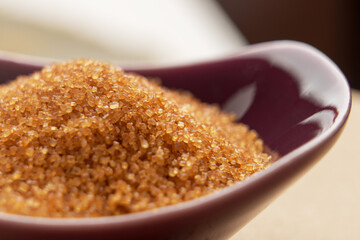 Red bowl of brown cane sugar. Organic sweet ingredient. Macro