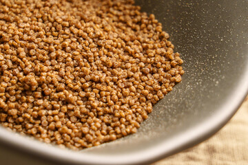 Dietary gluten-free buckwheat couscous in grey bowl close-up. Uncooked dry ingredient. 