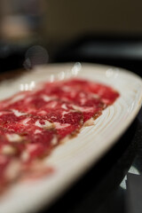 A white plate of raw beef slices ingredient in hot pot restaurant.