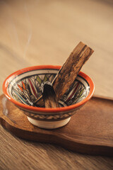 Smoldering Palo Santo Sticks in Colorful Ceramic Bowl on Wooden Tray