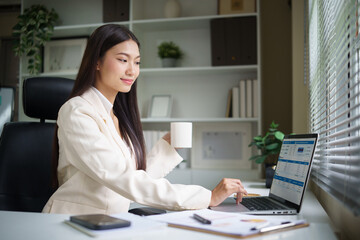 Professional businesswoman working on her laptop, analyzing data and reports in a bright office.