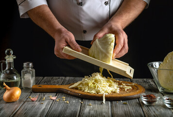 A chef skillfully shreds cabbage using a cutting board and a grater, surrounded by onions and...
