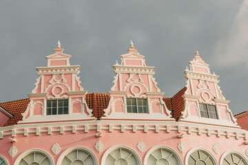 Historic pink building showcases intricate architectural details in a charming town under a moody sky