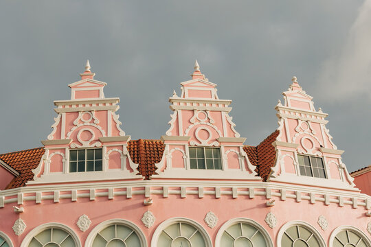 Historic pink building showcases intricate architectural details in a charming town under a moody sky