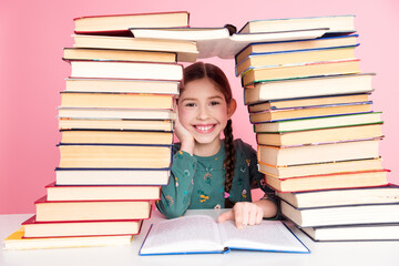 Smiling young girl with braids surrounded by colorful stacked book showing joy of learning in vibrant setting