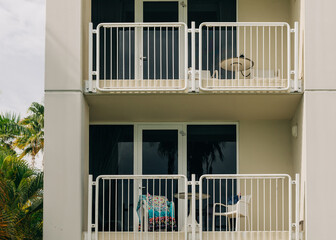 Two balconies with chairs and a table overlooking palm trees in a tropical setting during the day