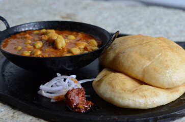 Popular North Indian dish chole bhature – spicy chickpea curry served with deep-fried fluffy...