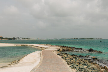 Walking along a serene coastal pathway beside turquoise waters at midday