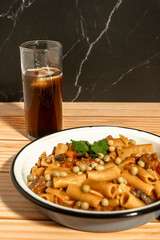 Delicious pasta with meat and peas served with soda on wooden table