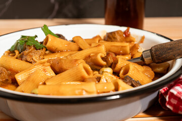 Steaming hot beef and mushroom tortiglioni pasta dish garnished with parsley