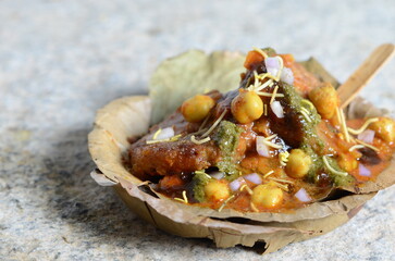 Popular Indian street food aloo tikki chole chaat – crispy potato patties topped with spicy chickpea curry, chutneys, curd, onions, and sev – flavorful North Indian snack