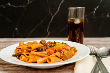 Delicious pasta with meat and vegetables enjoying with a refreshing drink