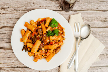 Delicious pasta with beef stew, vegetables and parsley on rustic wooden table