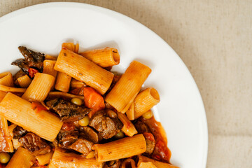 Delicious beef stew with rigatoni pasta, peas, carrots, and mushrooms on white plate