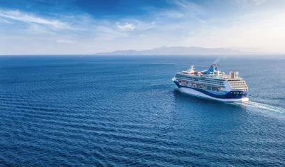 Fototapeten Panoramic aerial rear view of a cruise ship sailing over blue ocean with copy space as a banner for cruise travel © moofushi