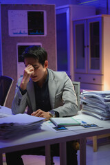 Stressed asian businessman having headache working late at night in office